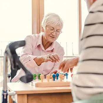 Bild einer Seniorin, die ein Brettspiel spielt